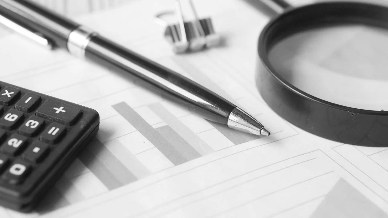 Uma mesa corporativa com documentos financeiros, gráficos e calculadora